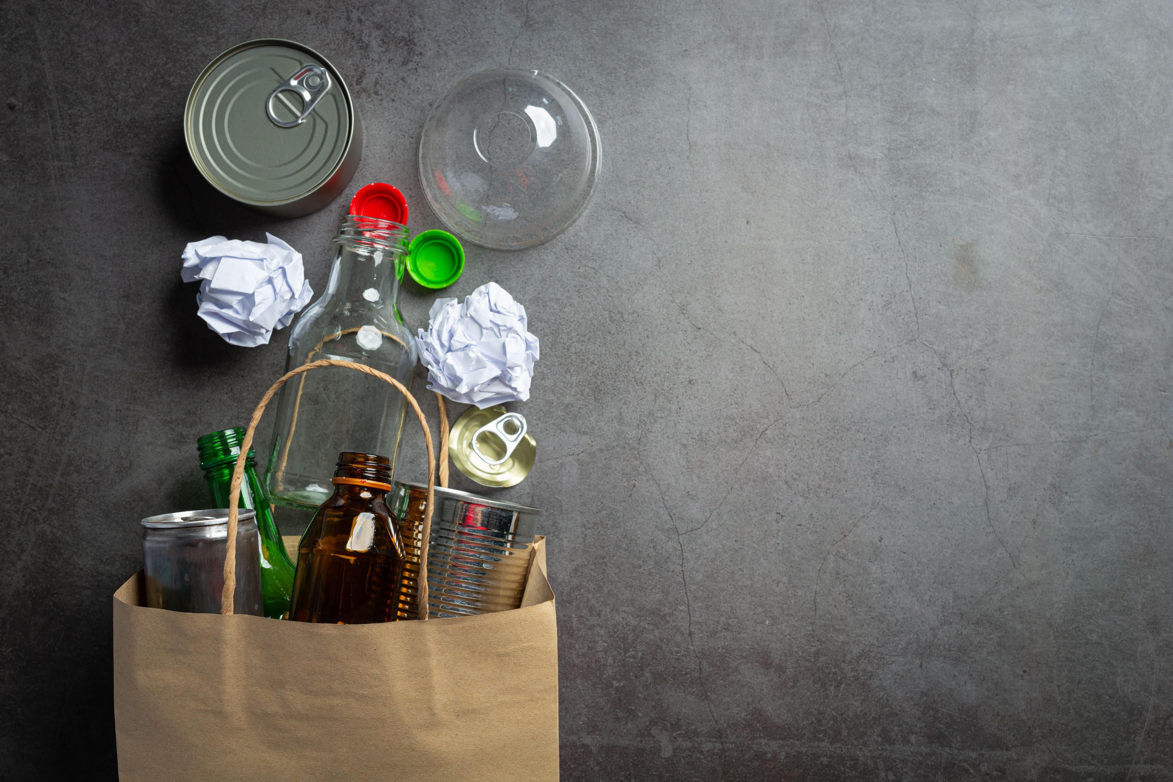 l'immagine rappresenta un sacchetto di carta contenente varie tipologie di rifiuti domestici su fondo grigio
